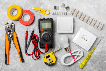 Electrician equipment on marble background with copy space.Top view.Electrician tool set.Multimeter, tester,screwdrivers,cutters,duct tape,lamps,tape measure and wires.Flet lay.