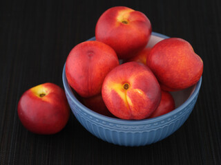 Freshly harvested nectarines in a blue bowl on a black mat