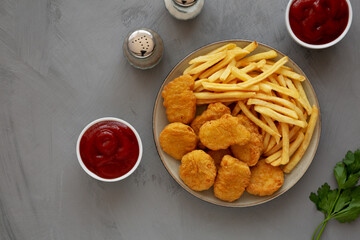 Homemade Chicken Nuggets and French Fries with Ketchup on gray background, top view. Flat lay, overhead, from above. Copy space.