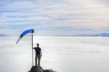 Photo of a man proudly standing on top of a mountain in Bariloche, Argentina, holding a flag