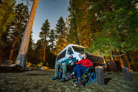 Couple gazes at the stars while camping with their van.