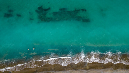 Aerial view from a flying drone people swimming in the sea on a holiday resort.