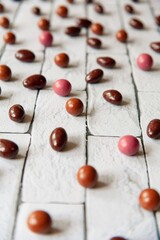 Fototapeta na wymiar Dragee nuts in chocolate on a background of white bricks