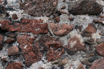 Pattern of an medieval house wall surface made of stones of different size, fastened with cement mortar
