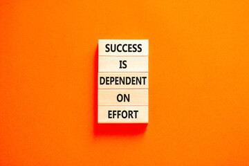 Success and effort symbol. Concept words Success is dependent on effort on wooden block. Beautiful orange table orange background. Business success and effort concept. Copy space.