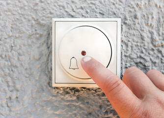 hand ringing on doorbell on pvc front door

