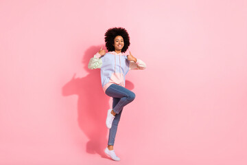 Fototapeta na wymiar Full length photo of sweet confident small kid wear sweatshirt showing two thumbs up jumping high isolated pink color background