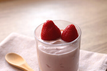 Bowl of strawberry yogurt with two fresh strawberries on the top. Selective focus.