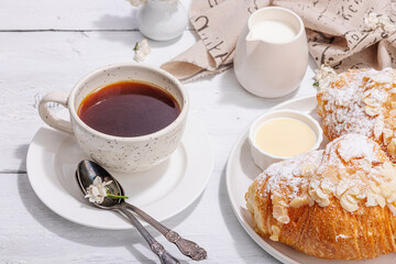 Good morning concept. Breakfast with cup of coffee and fresh croissant. Sweet creamy sauce