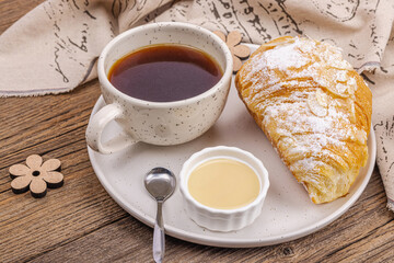 Good morning concept. Breakfast with cup of coffee and fresh croissant. Sweet creamy sauce