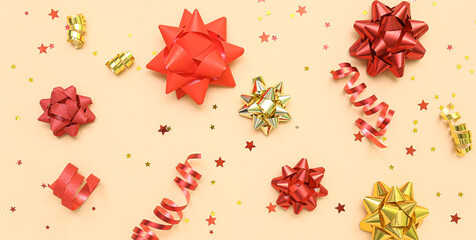 Decorative bows and streamers on beige background, top view