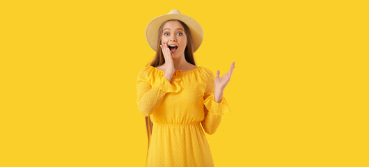 Surprised young woman in dress on yellow background
