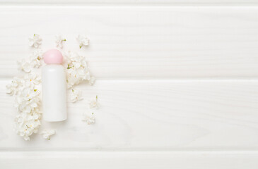Composition with cosmetic bottle and flowers on wooden background, top view
