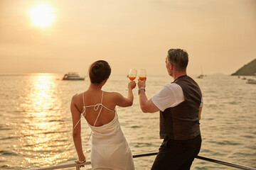 back couple drinking orange juice in luxury yacht