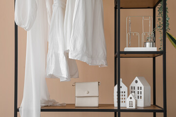 Fototapeta na wymiar Shelving unit with clothes and accessories near beige wall