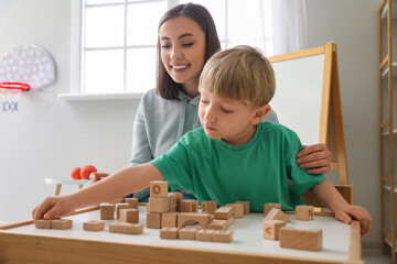 Little boy and nanny playing with cubes at home