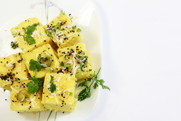 traditional indian gujarati snack khaman dhokla fast food dish made from chana dal,closeup in white background,top view with selective focus,copy space