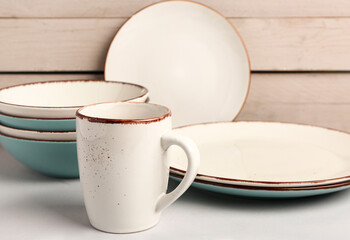 Set of different dishes on table near white wooden wall