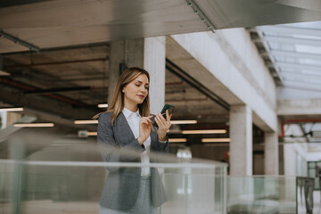 Young business woman using mobile phone in the office hallway