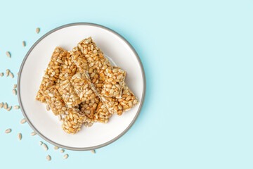 Plate with tasty kozinaki and sunflower seeds on blue background