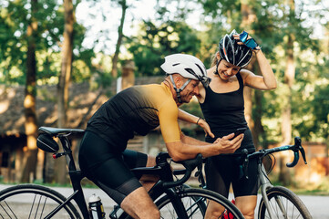 Fototapeta na wymiar Couple using smartphone while taking a break from bicycle riding