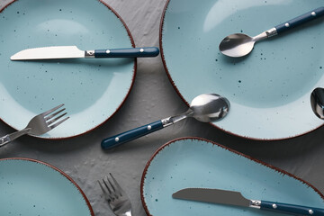Silver cutlery with blue plates on grey table