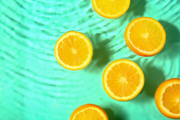 Slices of fresh orange in water on turquoise background