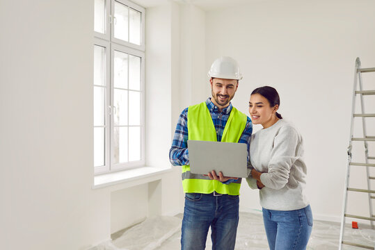 Woman apartment owner discussing home design plan with foreman. Professional builder showing project of renovation to young woman using laptop computer. Building and home renovation