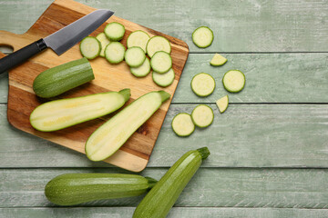Board with slices of fresh zucchini on green wooden background