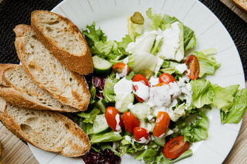 close up of a healthy delicious salad with tomatoes, cheese, chicken, vegetables and baguette. A light, healthy meal rich in protein. Caesar salad