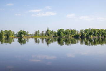 Tranquil scene with a forested island reflected in a calm river in early morning, nobody