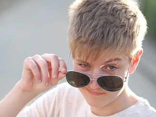 Outdoor portrait of a friendly caucasian blue-eyed teenager in  sunglasses - 608820301