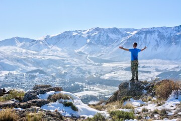 Photo of a man standing triumphantly on top of a snow-covered mountain in Argentina
