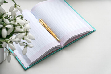 snowdrops, notepad and golden pen. flat layout.