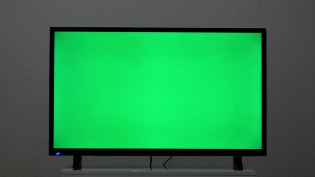 LcD smart TV with green screen on a grey wall background in the living room. Concept. Chroma key screen of a modern TV.