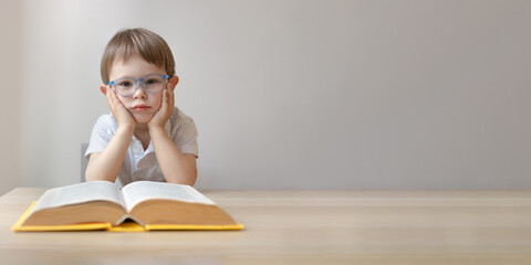 portrait of a smart little boy in glasses with an open book,  copy space