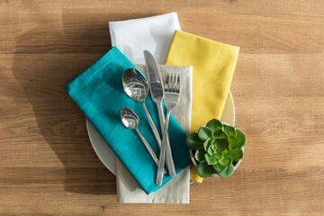 A wooden table setting with blue napkins, silver cutlery and ornate spoons, ready for a luxurious...