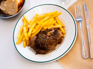 Appetizing baked pork cheeks served with vegetable garnish of fried potatoes. Typical Spanish cuisine