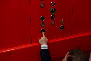 small boy pressing button in red elevator