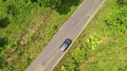 AERIAL TOP DOWN: Black SUV car travelling through beautiful tropical countryside