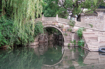 Fototapeta na wymiar old bridge over the river with reflections and willow tree
