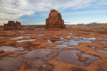 Fototapeta na wymiar Rock formations and puddles with reflections at Arches National Park, Utah, USA