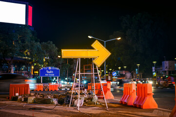 road repair with yellow arrow sign at night 