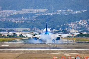 着陸しタイヤから煙を上げるジェット旅客機
