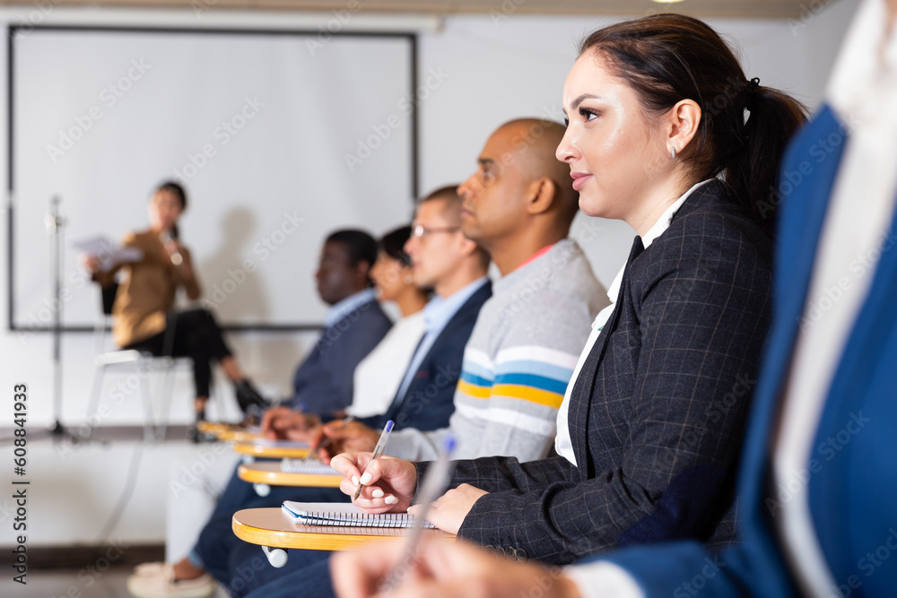 Canvas Prints Young focused woman sitting and listening to speaker at business conference