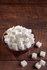 White sugar cubes in wooden bowl.