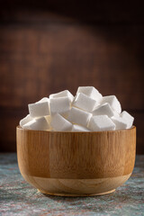 Fototapeta na wymiar White sugar cubes in wooden bowl.