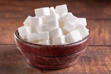 White sugar cubes in wooden bowl.