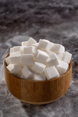 White sugar cubes in wooden bowl.