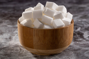 White sugar cubes in wooden bowl.